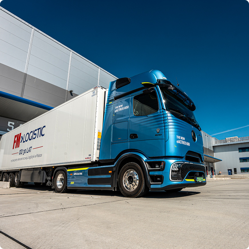 FM Logistic truck parked at a logistics facility under a clear blue sky.